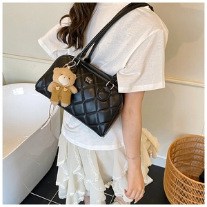 Close-up of quilted black bowling bag featuring a cute plush bear charm and sleek hardware