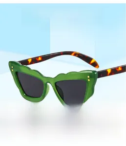 Detail of green scalloped frame sunglasses with tortoiseshell temples and gold rivets