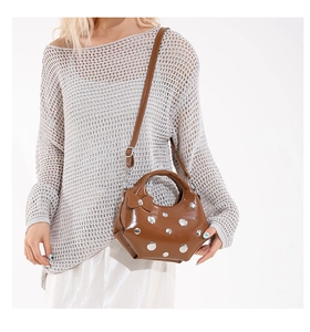 Gros plan du sac à main brillant marron avec clous argentés porté par un mannequin