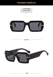 Detail of square sunglasses with black grey lenses and gold trim on shiny black frames