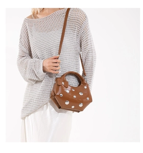 Detail of brown faux leather bag with silver rivets, bow accent and shoulder strap