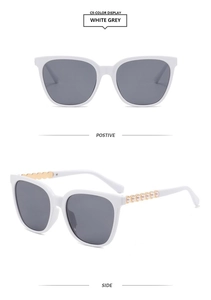 Detail of square white sunglasses with gold temples and pearl accents for luxury fashion