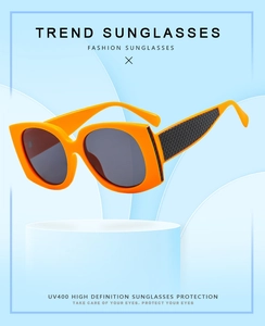 Detail of bright orange square sunglasses with black textured grid patterns on temples