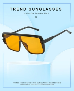 Detail of square oversized sunglasses with black frame, orange lenses, and UV400 protection