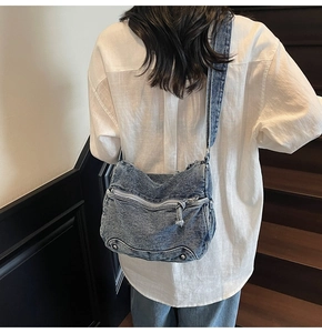 Dettaglio borsa a tracolla in denim blu lavato con rivetti argento e chiusura lampo