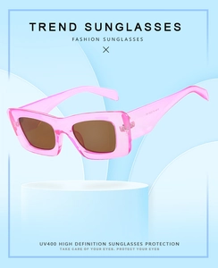 Close-up of pink square sunglasses with brown UV400 lenses on a modern podium