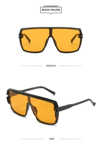 Detail view of bold square sunglasses with black frames and translucent orange lenses