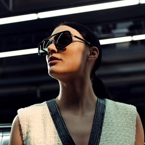 Modische übergroße quadratische schwarze Sonnenbrille mit goldenen Metallbügeln am Model
