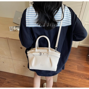 Detail of off-white lychee texture leather bag with elegant metal buckle and strap