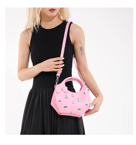 Detail of pink patent leather crescent bag featuring silver studs and a bow decoration