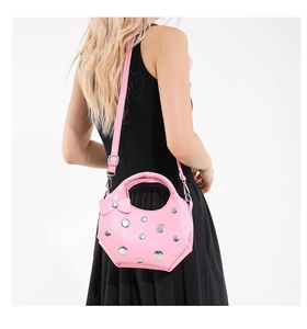 Detail of pink patent leather crescent bag with silver rivets and bow detail