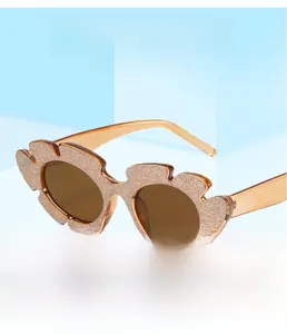 Detail der Glitzer-Blumensonnenbrille mit runden braunen Gläsern und orangen Bügeln