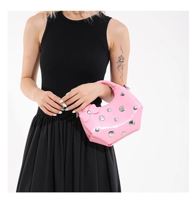 Détail d'un sac à main en cuir verni rose vif avec clous argentés et nœud sur le côté