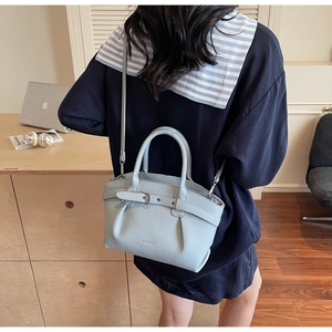 Close-up of light blue leather handbag with lychee texture and adjustable strap detail