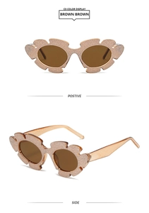 Detailansicht der luxuriösen Sonnenbrille mit glitzerndem Blumenrahmen und braunen Gläsern