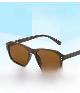 Détail de lunettes de soleil carrées marron vintage avec rivets sur fond bleu clair