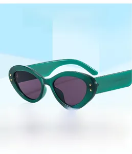 Detailed view of green cat-eye sunglasses with gold star accents on a blue background
