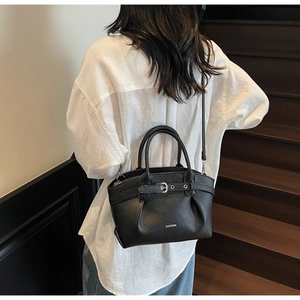 Detail of black textured leather bucket bag with metal buckle and adjustable strap