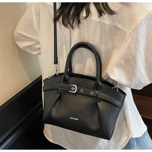 Detail of a black litchi leather handbag with silver buckle and adjustable shoulder strap