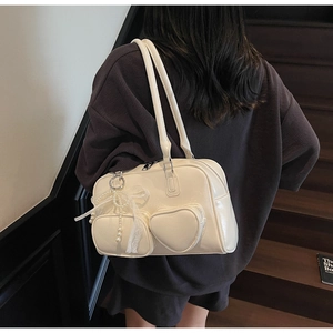 Detail of beige glossy bowling bag with heart pocket, lace bow and pearl pendant charm