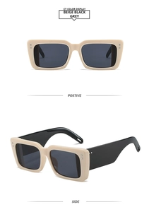 Detail view of beige rectangle sunglasses with wide black temples and metal rivet accents