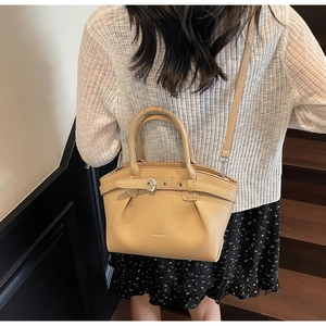 Detailed view of beige pebble grain leather handbag with adjustable strap and logo