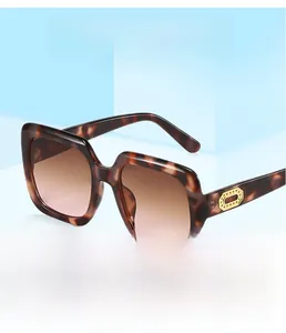 Detail of square tortoiseshell sunglasses with golden oval accents on light blue background