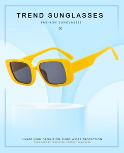 Macro detail of yellow square sunglasses with UV400 protection on a blue pedestal