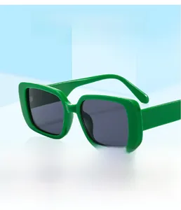 Detail of square green sunglasses with dark lenses on a light blue geometric background