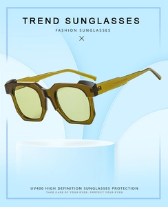 Detail view of olive green geometric sunglasses with UV400 lenses on light blue pedestal
