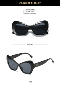 Detail view of retro cat-eye sunglasses with gold clover accent on black frames