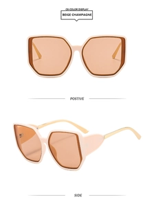 Macro detail of oversized square beige frames with golden metal temples and amber lenses