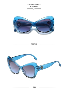 Detail view of cat eye sunglasses in translucent blue frame with golden temple logo