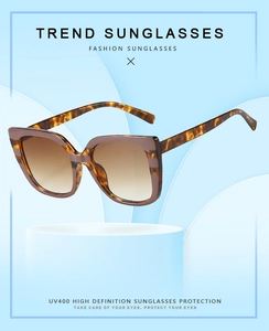 Detail of tortoise shell sunglasses with UV400 gradient lenses on a blue display
