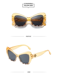 Detail of candy-colored cat-eye sunglasses with yellow frames and metal S-shaped temple logo