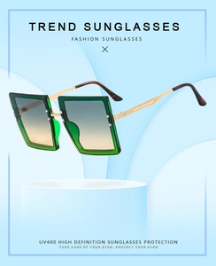 Detail of square oversized emerald green sunglasses with gold metal temples and UV400 lenses
