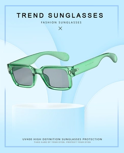 Green translucent square frame sunglasses displayed on a blue pedestal with UV400 protection
