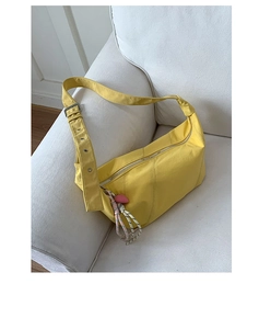Close-up of bright yellow nylon hobo bag with pink heart charm on a white sofa
