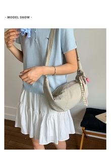 Detail of crescent crossbody bag with woven pendant and heart charm decoration