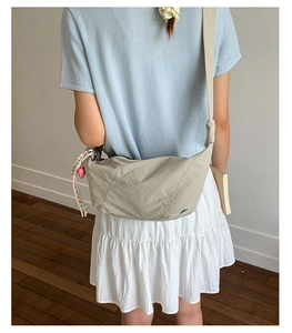 Back view of a casual light grey nylon crossbody dumpling bag with pink heart charm