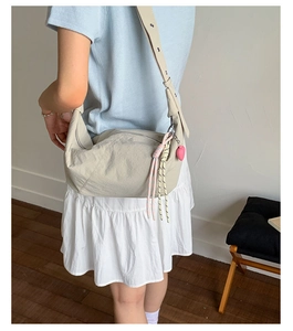 Detail view of beige nylon crescent bag with colorful cord and pink heart charm