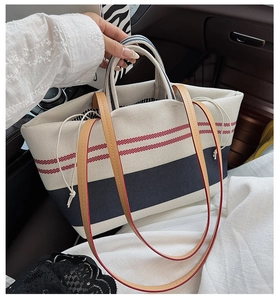 Detail der gestreiften Canvas-Tasche mit braunem Lederriemen und Kordelzugverschluss