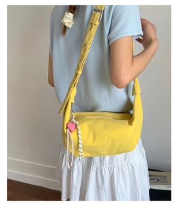 Detail view of yellow crescent crossbody bag with adjustable strap and heart charm