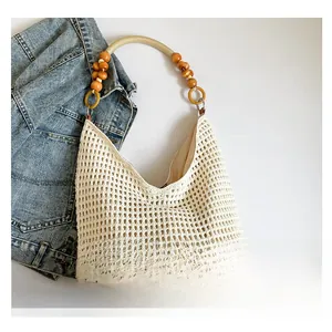 Detail of hollow knit tote bag featuring wooden bead handle and brown leather patch