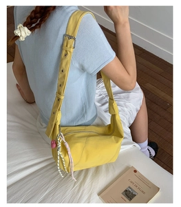 Detail of yellow nylon hobo bag with adjustable strap and pink heart charm accessory