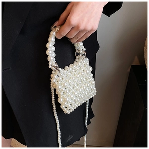 Close-up of handmade pearl woven handbag with metallic buckle and shoulder chain