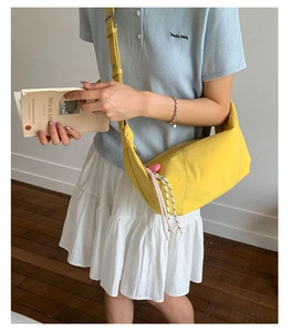 Detail of yellow canvas crossbody bag with pink heart charm and adjustable wide strap