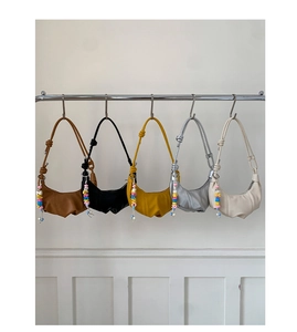 Detail of five pleated crescent bags in diverse colors with colorful letter bead charms
