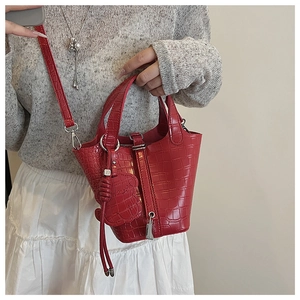 Detail of red crocodile pattern mini bucket bag with M-pendant and leather strap