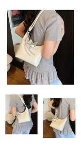 Détail du sac sous le bras crème avec finition brillante et breloque étoile argentée